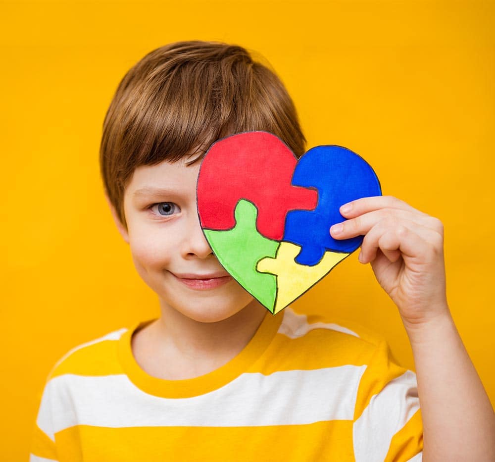 child holding a puzzle over half of his face